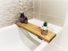 a wooden shelf in the middle of a bathtub with two bottles on it next to a candle holder