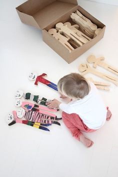 a toddler playing with wooden toys on the floor in front of a cardboard box