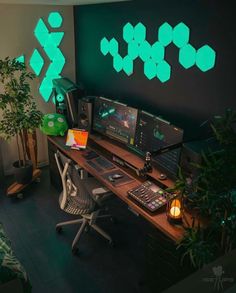 a computer desk topped with two monitors next to a plant