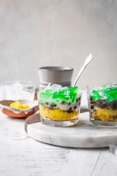 two desserts with green icing and other toppings on a marble platter