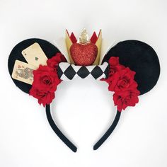 a mickey mouse ears headband with red flowers and a crown on it's head