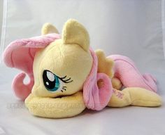 a little pony laying on its side with pink ears and tail, eyes wide open