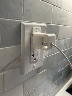 an electrical outlet is plugged into the wall in a kitchen with gray tiles on it