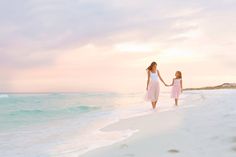 mother and daughter walking on the beach at sunset