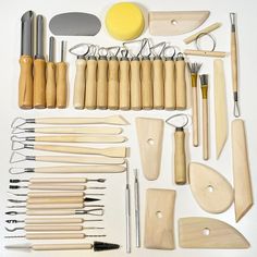 an assortment of kitchen utensils laid out on a white surface with wooden handles