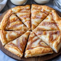 a wooden plate topped with sliced pizza on top of a table