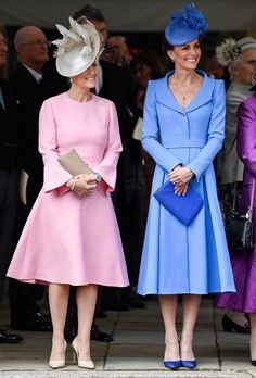 two women standing next to each other wearing blue and pink dresses with matching hats on them