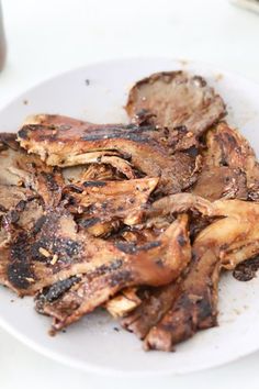 a white plate topped with cooked meat on top of a table