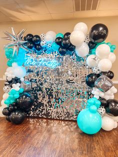 a table topped with balloons and black and white decorations on top of a wooden floor