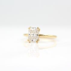 an engagement ring with a square cut diamond in the center, on a white surface