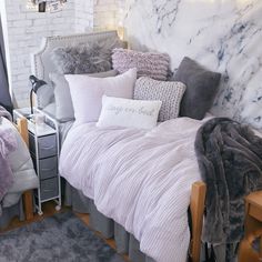 a bed with pillows and blankets on top of it in a bedroom next to a brick wall