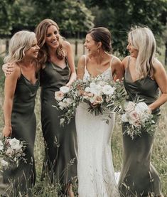 three bridesmaids standing in the grass with their bouquets smiling at each other