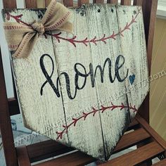 a wooden sign with the word home painted on it and a bow hanging from its back