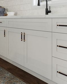 a kitchen with white cabinets and black handles