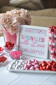 a table topped with candy and candies next to a framed sign that says sprinkled with love