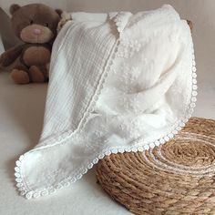 a teddy bear sitting next to a basket with a white blanket on top of it