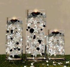 three clear glass vases with lights in them on the grass next to each other