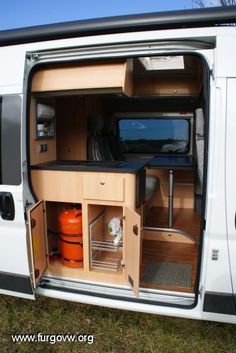 the inside of a van with its door open and some orange barrels in the back