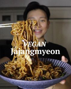 a person holding a bowl of noodles with chopsticks in their hand and the words vegan jahangyeon above it