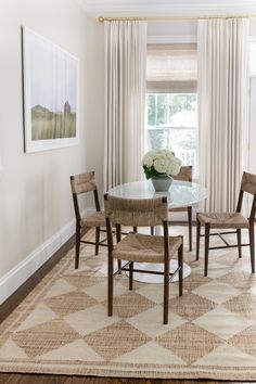 a dining room table with four chairs and a rug on the floor in front of it