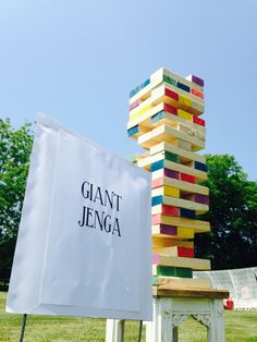 a giant stack of books sitting on top of a wooden bench next to a giant sign