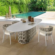 an outdoor dining table with chairs around it and a swimming pool in the back ground