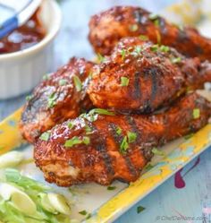 grilled chicken wings with ketchup and green onions on a yellow platter