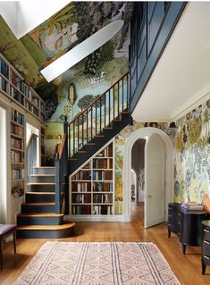 a room with a staircase, bookshelf and painting on the wall