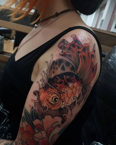 a woman with red hair has a fish tattoo on her arm