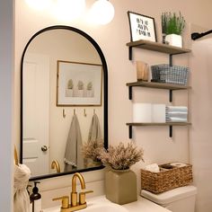 a bathroom with a sink, mirror and shelves on the wall above it's toilet