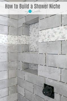 a bathroom with white and gray tile on the walls, shower niches in the middle