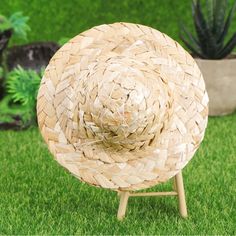 a large woven hat sitting on top of a wooden stand in the middle of grass