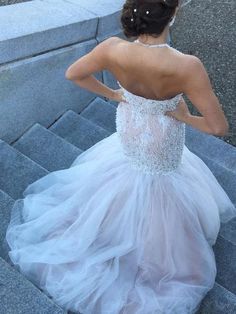 a woman in a wedding dress walking up some steps with her back to the camera