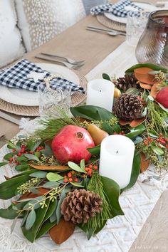 the table is decorated with pine cones, apples and greenery