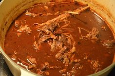 a pot filled with meat and sauce on top of a stove