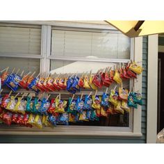 bags of chips are hanging on a clothes line in front of a window