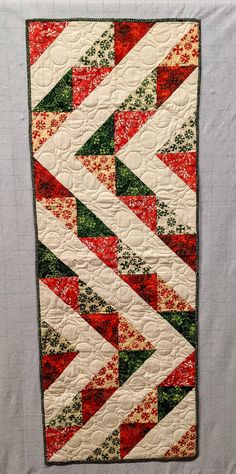 a quilted wall hanging with red, green and white designs on it's side