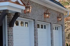 two garage doors and three lights on the side of a brick building