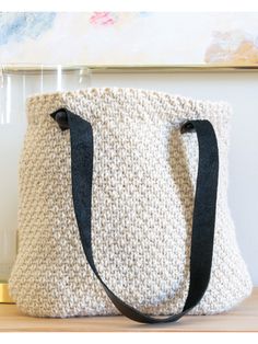 a crocheted bag sitting on top of a wooden table