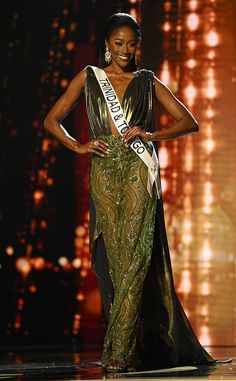 a woman in a black and gold dress is standing on the stage with her hands on her hips