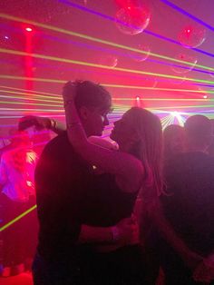 a man and woman dancing in a club with neon lights on the walls behind them