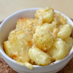 a white bowl filled with macaroni and cheese sitting on top of a table