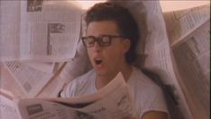 a man laying in bed reading a newspaper and making a face with his mouth wide open