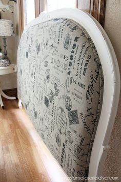 a white headboard with writing on it in front of a wooden floor and window