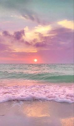 the sun is setting over the ocean with waves coming in to shore and pink clouds