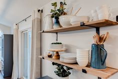 the shelves are filled with plates and bowls on them, along with other kitchen utensils