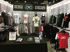 an exhibit booth with t - shirts and other items for sale on the table in front of it