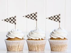 three cupcakes with white frosting and checkered flags