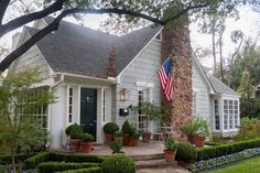 an american flag is hanging on the front door of a white house with potted plants