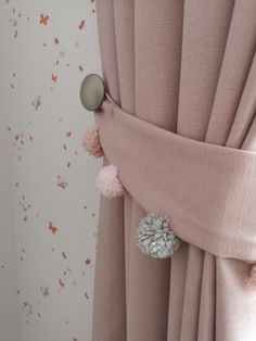 pink curtains with pom poms hanging on them